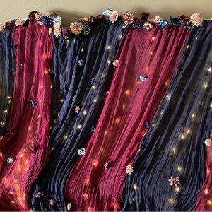 Backdrop with wine and navy muslin, Sola flowers, and lights, and 2 chair ties